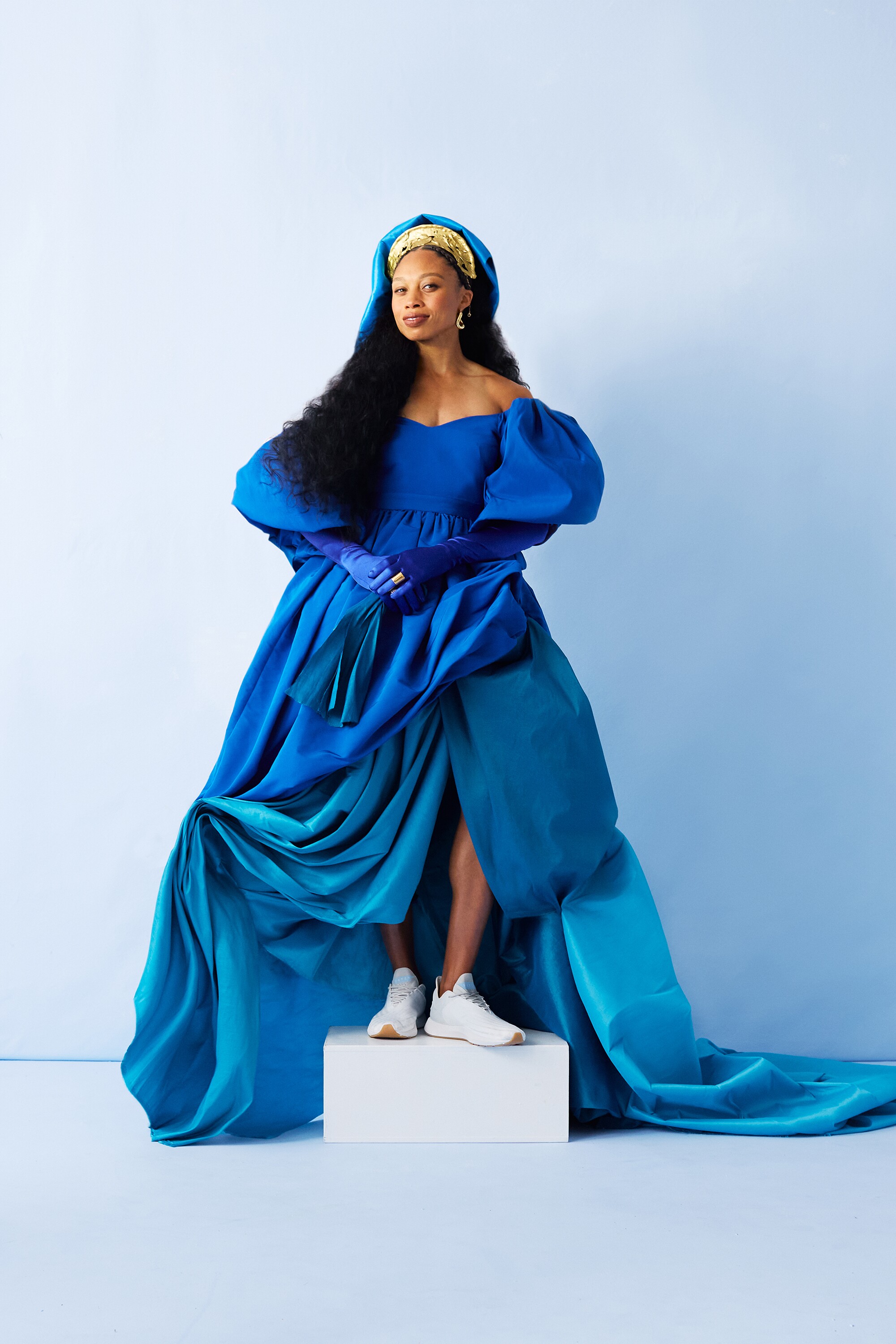 Allyson Felix in a voluminous blue dress with puffed sleeves and a blue headpiece wearing her white Saysh sneakers.