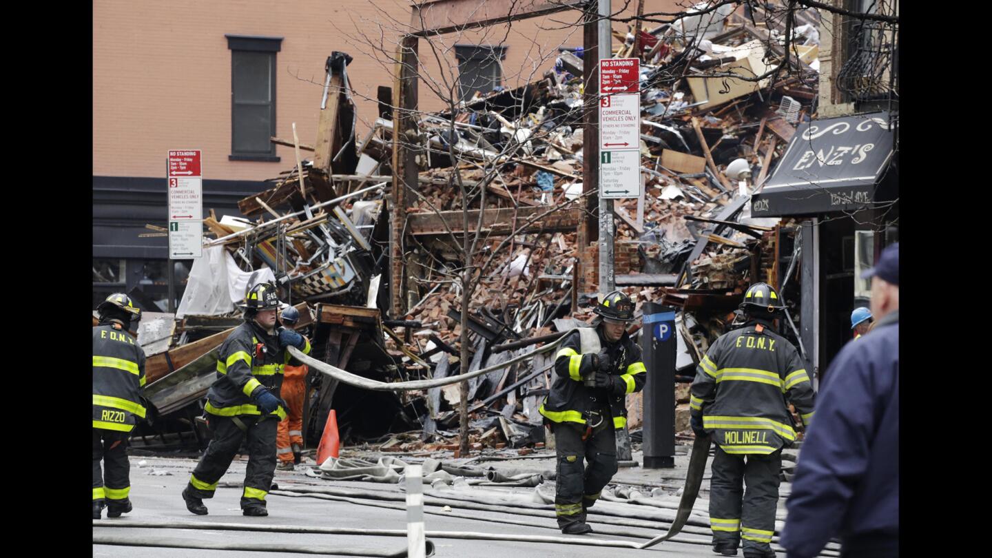 Firefighters roll up fire hoses at the site of an explosion and fire in the East Village neighborhood of New York on Friday.