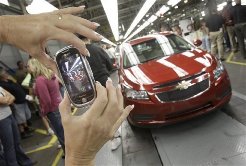 FILE - In this Sept. 8, 2010 file photo, auto worker Brenda Hedland takes a picture of the first Chevrolet Cruze compact sedan to come off the assembly line at a ceremony inside the GM factory in Lordstown, Ohio. General Motors dealers in the United States reported 232,538 total sales in April, a 26-percent increase versus April a year ago. (AP Photo/Amy Sancetta)