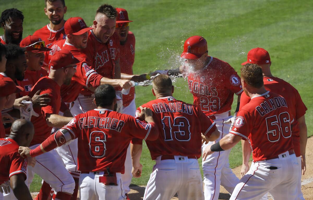 Angels rookie Matt Thaiss is splashed by his teammates while crossing home plate.