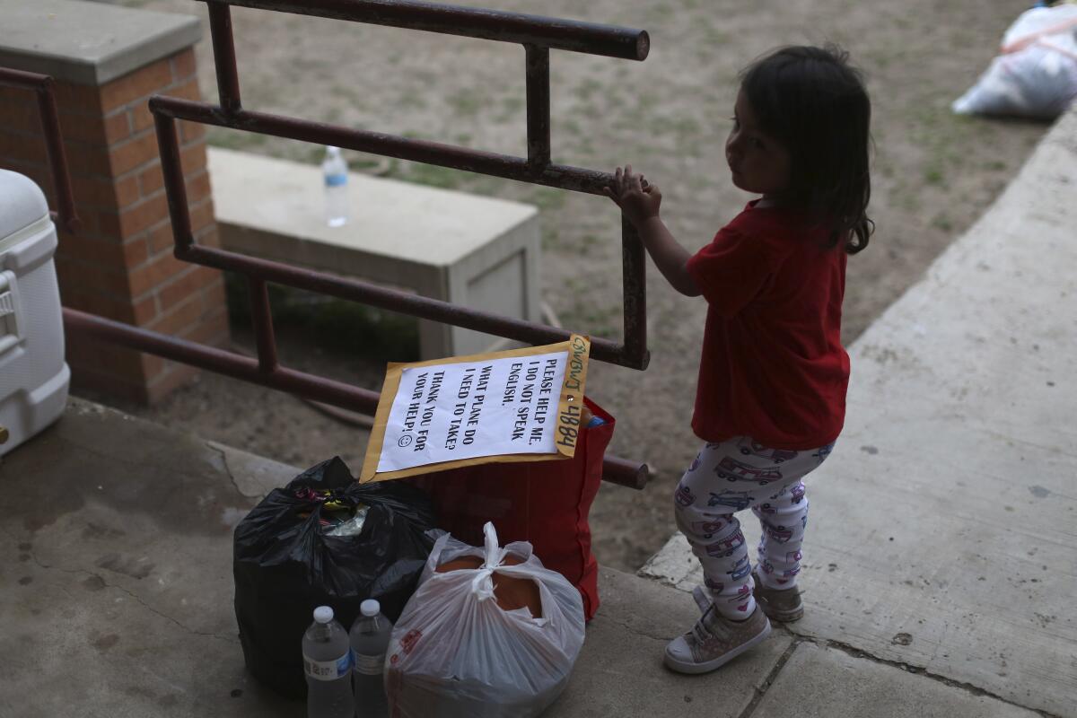A chid stands next to her family's belongings as they wait for transportation at Our Lady of Guadalupe Catholic Church in McAllen, Texas, on Palm Sunday, March 28, 2021. U.S. authorities are releasing migrant families at the border without notices to appear in immigration court, and sometimes without any paperwork at all. (AP Photo/Dario Lopez-Mills)