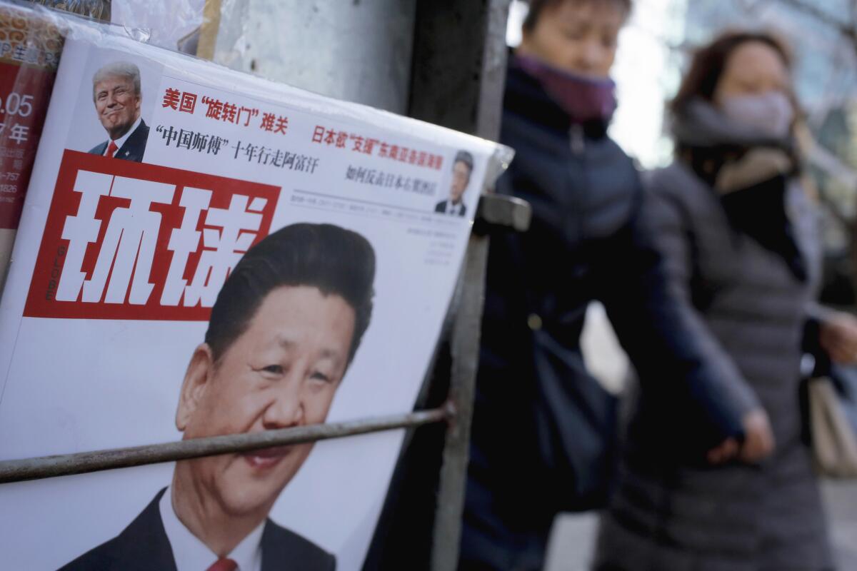 Women pass a Beijing news stand Thursday. The cover of a Chinese magazine featured photos of Chinese President Xi Jinping and U.S. President Donald Trump.