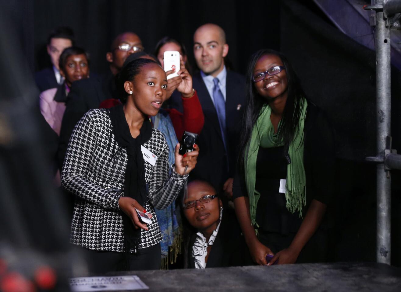 Members of the audience and press watch U.S. President Barack Obama from behind the bleachers as he participates in a town hall-style meeting with young African leaders at the University of Johannesburg in Soweto