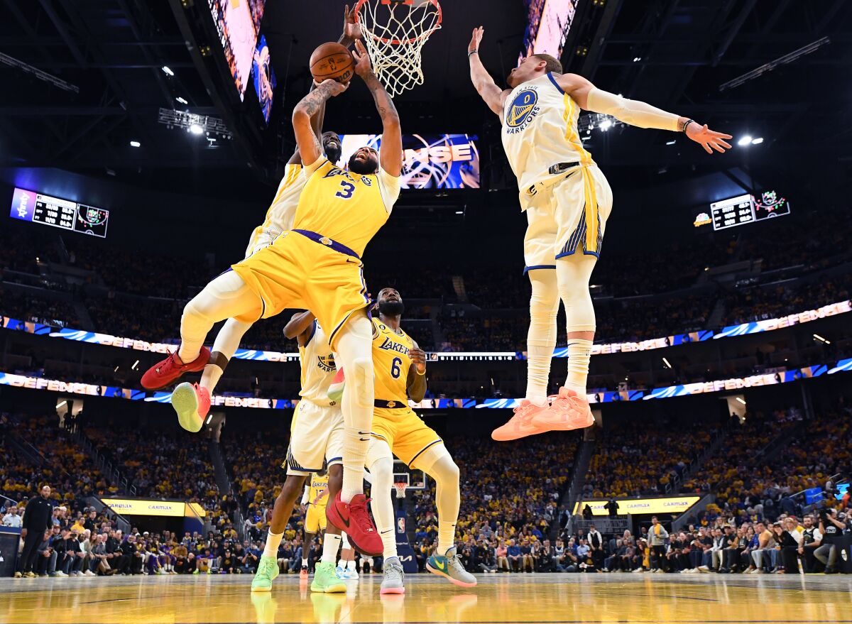 Lakers' Anthony Davis has his shot blocked by Golden State Warriors' Draymond Green as Donte Di'Vincenzo helps on defense.