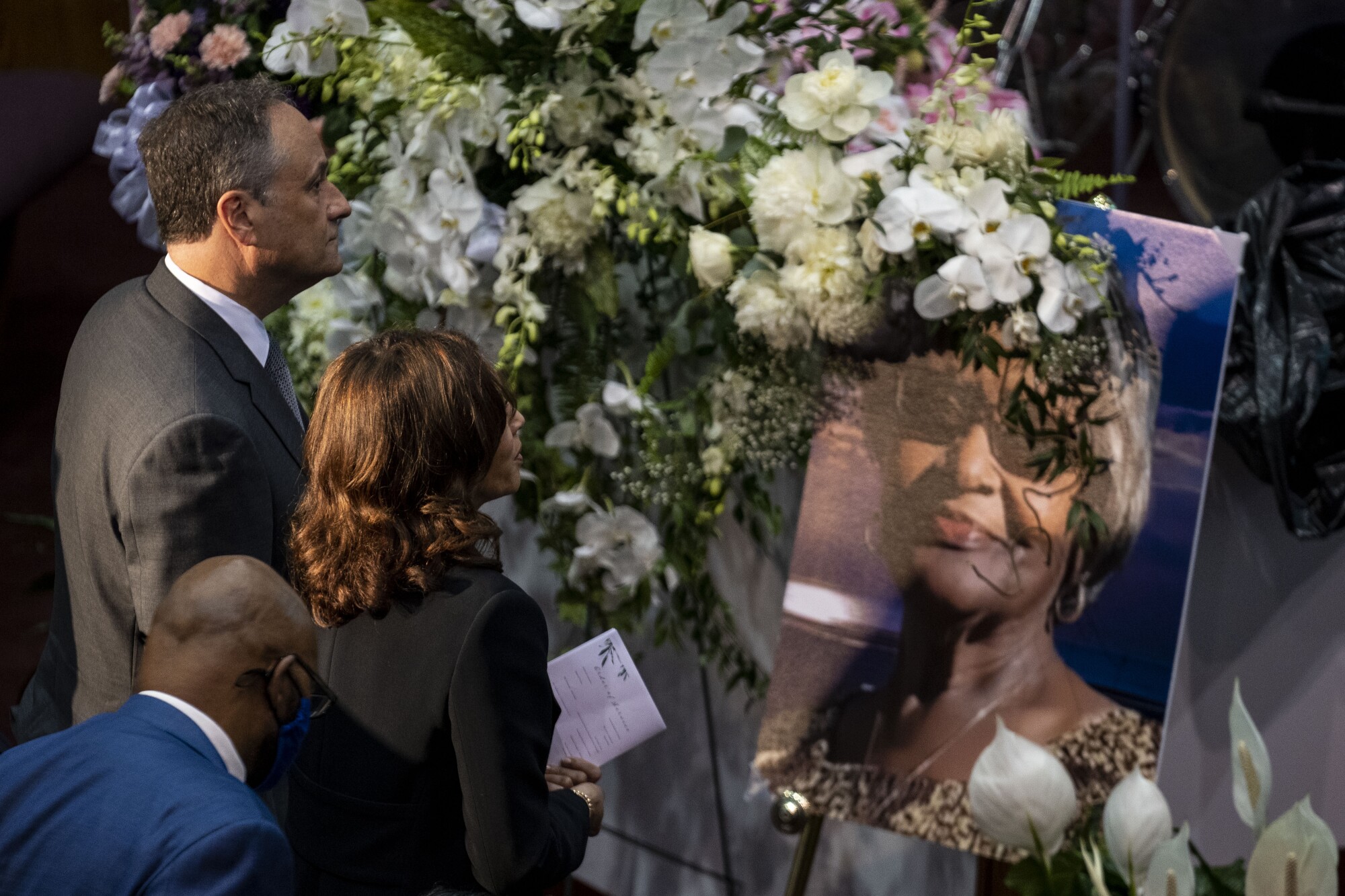 Kamala Harris ve İkinci Beyefendi Doug Emhoff, bir kadının büyük bir fotoğrafına bakıyor.