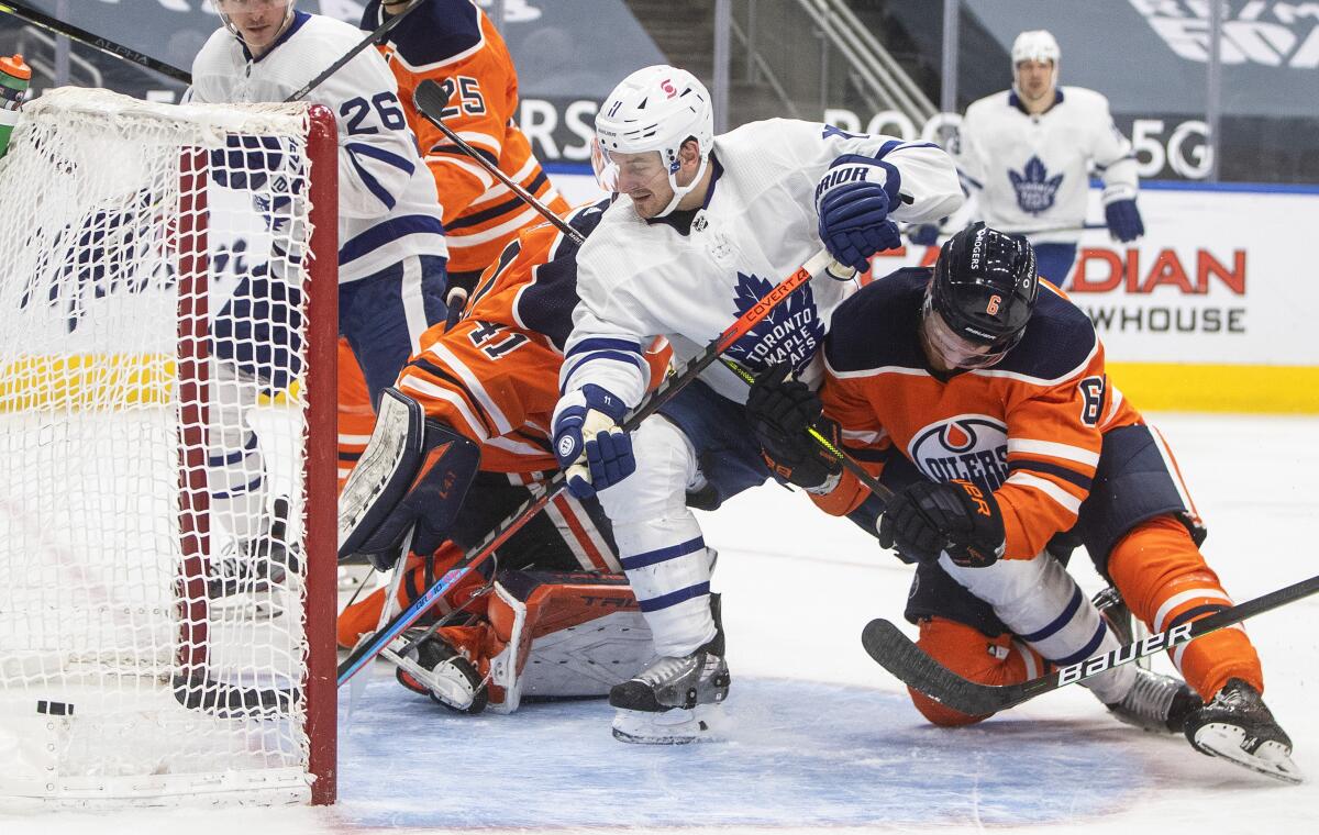 Edmonton Oilers goalie Mike Smith (41) gives up a goal to Toronto Maple Leafs' Zach Hyman (11) as Oilers' Adam Larsson (6) defends during the third period of an NHL hockey game Wednesday, March 3, 2021, in Edmonton, Alberta. (Jason Franson/The Canadian Press via AP)