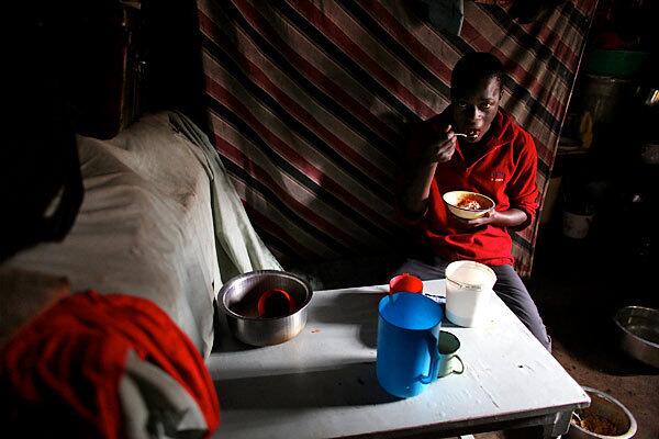 A Nairobi teen eats in a makeshift kitchen in the Kibera slum, where the nongovernmental organization Concern, in cooperation with local Kenyan groups, has launched a campaign to provide cash grants to help people start businesses or simply get back on their feet after suffering in the postelection violence of 2007.
