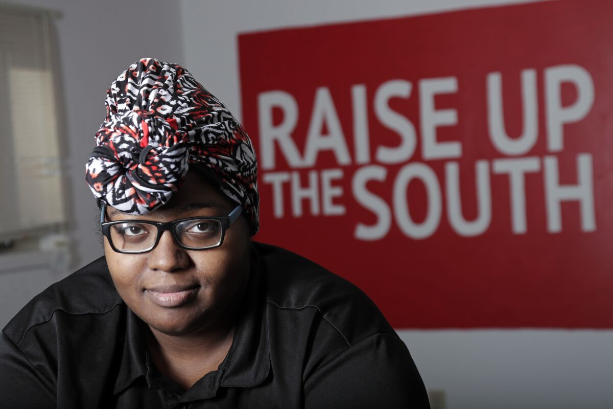 Food service worker Sheree Allen poses in the Raise Up offices, a branch of the Fight for $15 union, Thursday, Feb. 10, 2022, in Durham, N.C. After decades of decline, U.S. unions have a new reason for hope: younger workers. Sheree Allen was hoping for benefits when she joined the food service company Chartwells last August. Chartwells says it offers health care, paid time off and a 401 (k) plan to its workers, but Allen says she has never been given information about those benefits despite asking her superiors. When she tested positive for COVID in January, she had to stay home without pay. (AP Photo/Chris Seward)
