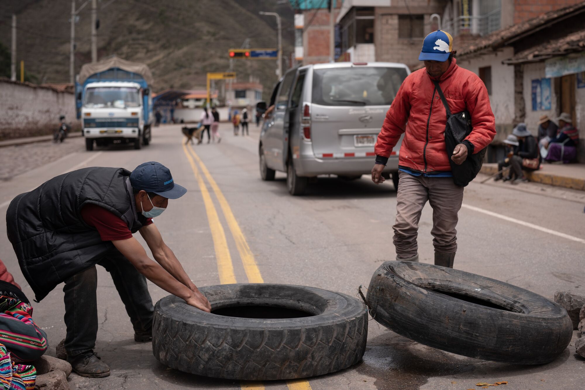Villagers pull tires into a roadway. 
