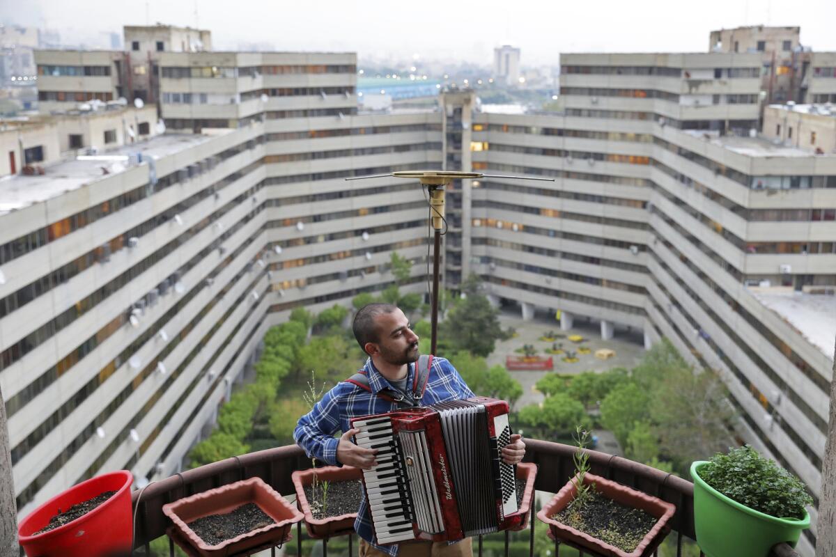 Fotografía del 8 de abril de 2020 de Behnam Emran, un músico autodidacta de 28 años, tocando el acordeón en la azotea de su casa durante la cuarentena debido al brote del nuevo coronavirus en Teherán, Irán. (AP Foto/Ebrahim Noroozi)