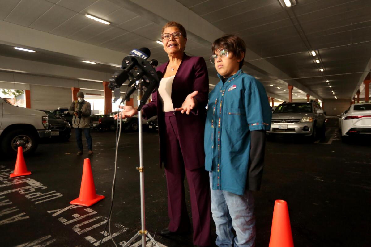 Karen Bass, standing with her grandson, speaks to reporters.