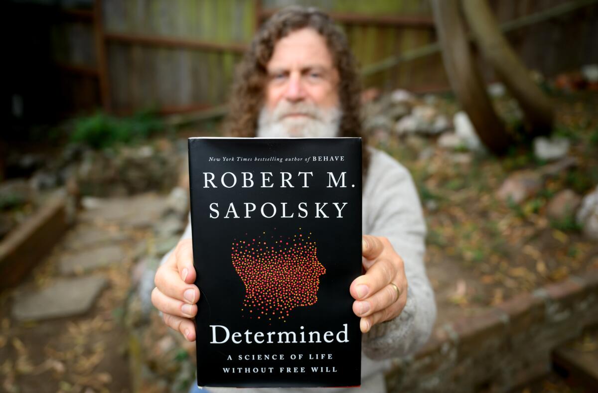 Robert Sapolsky holds up a copy of his book