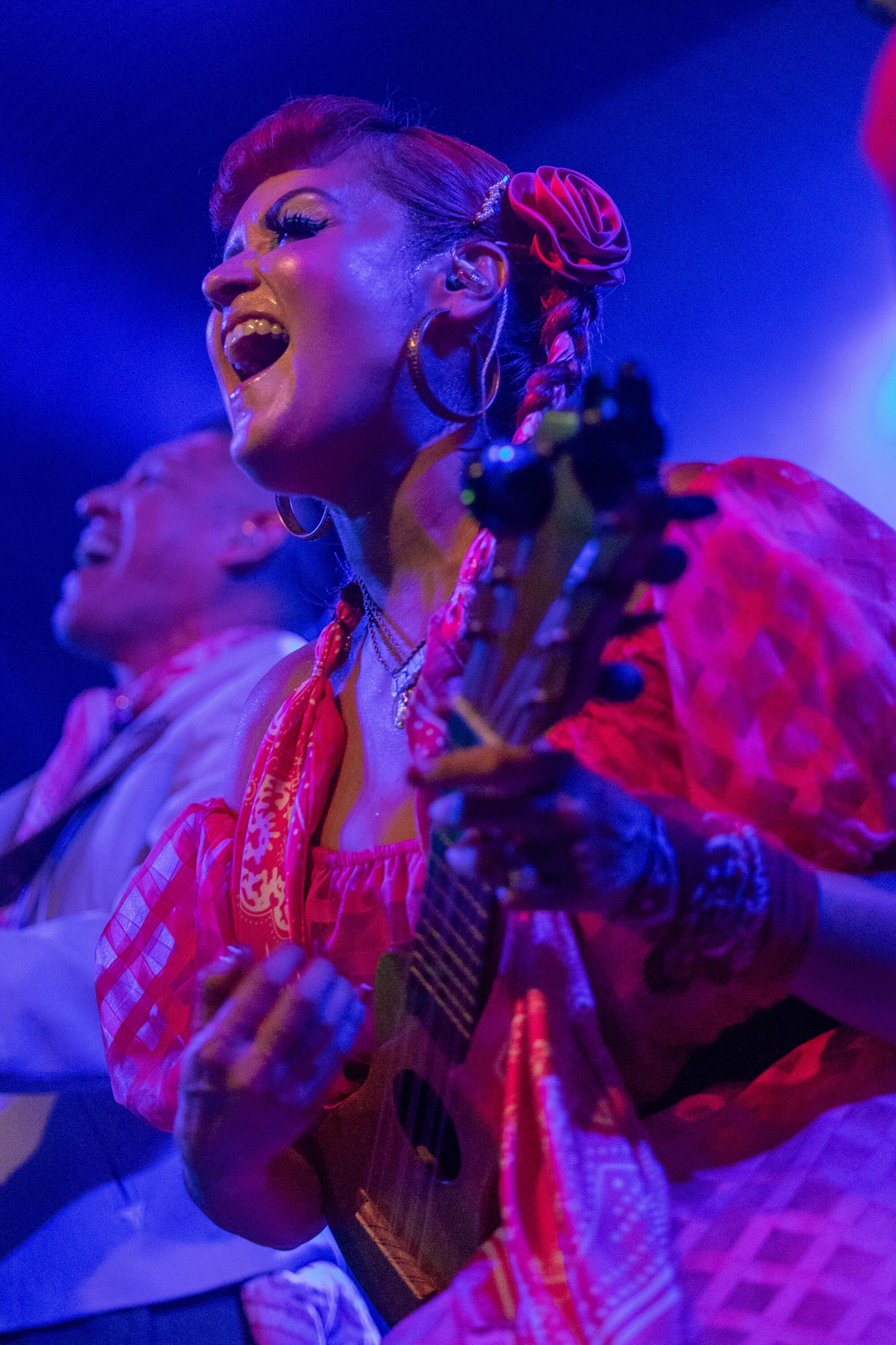 A woman bathed in blue light performs at a concert.