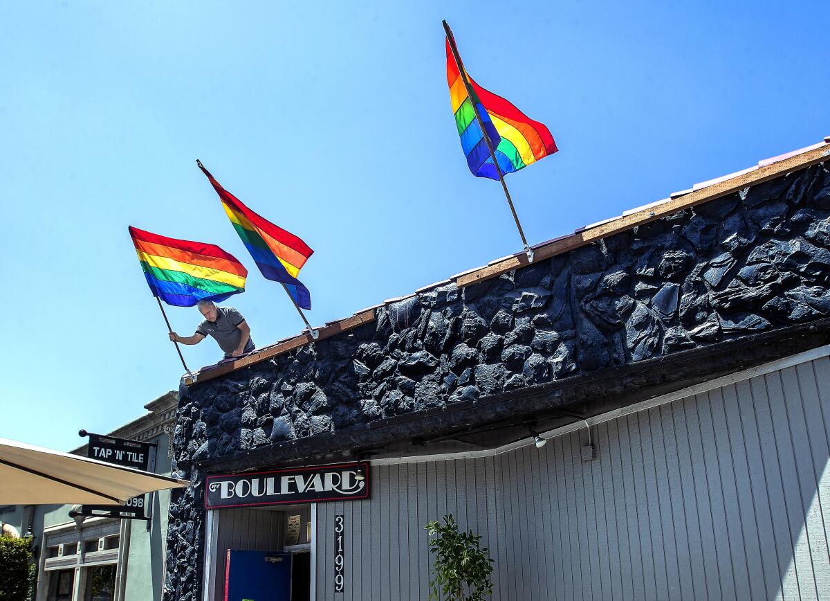 Steve Terradot places rainbow flags in their holders above the front entrance to the Boulevard.