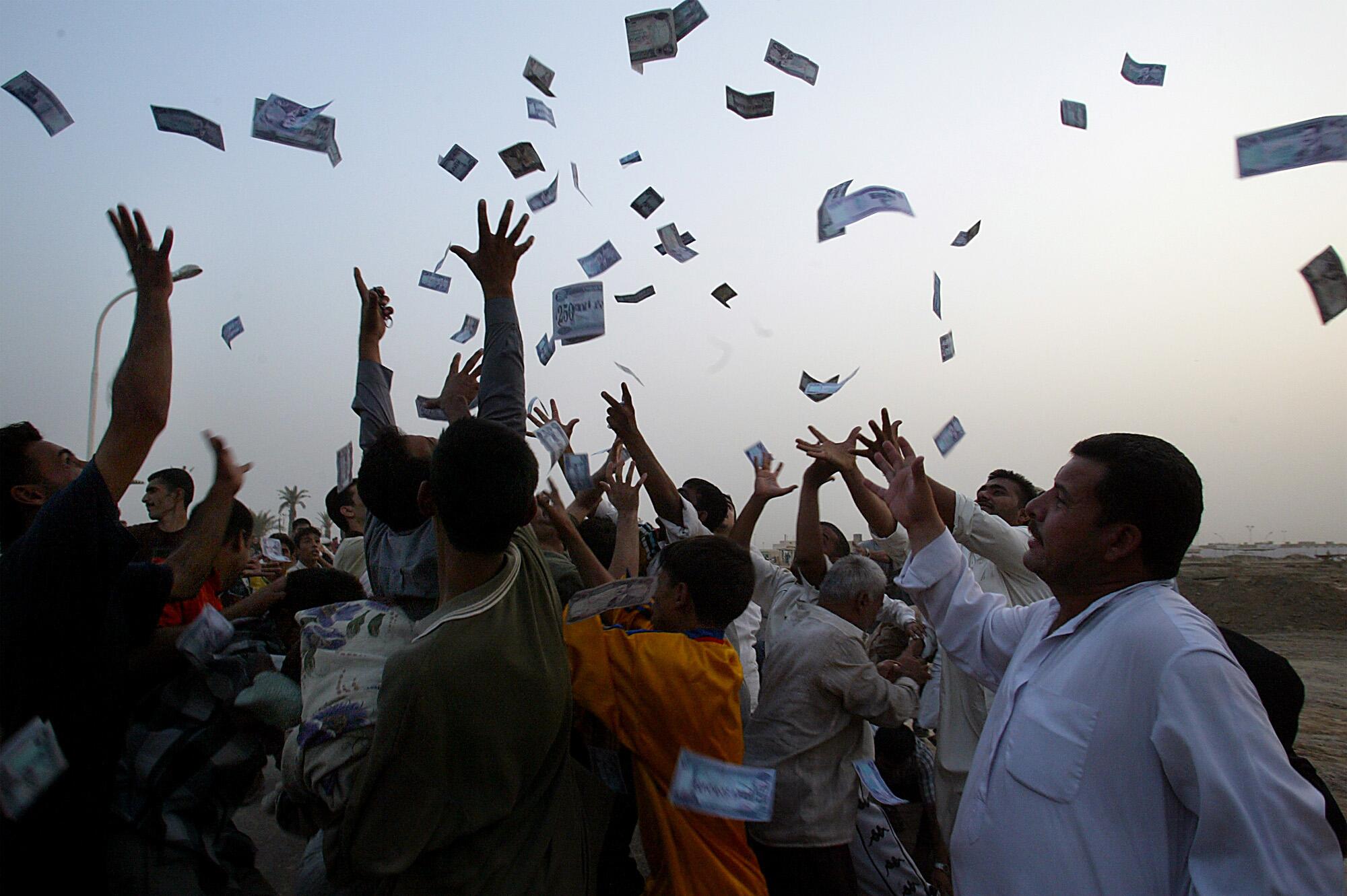 A group of people throw cash into the air