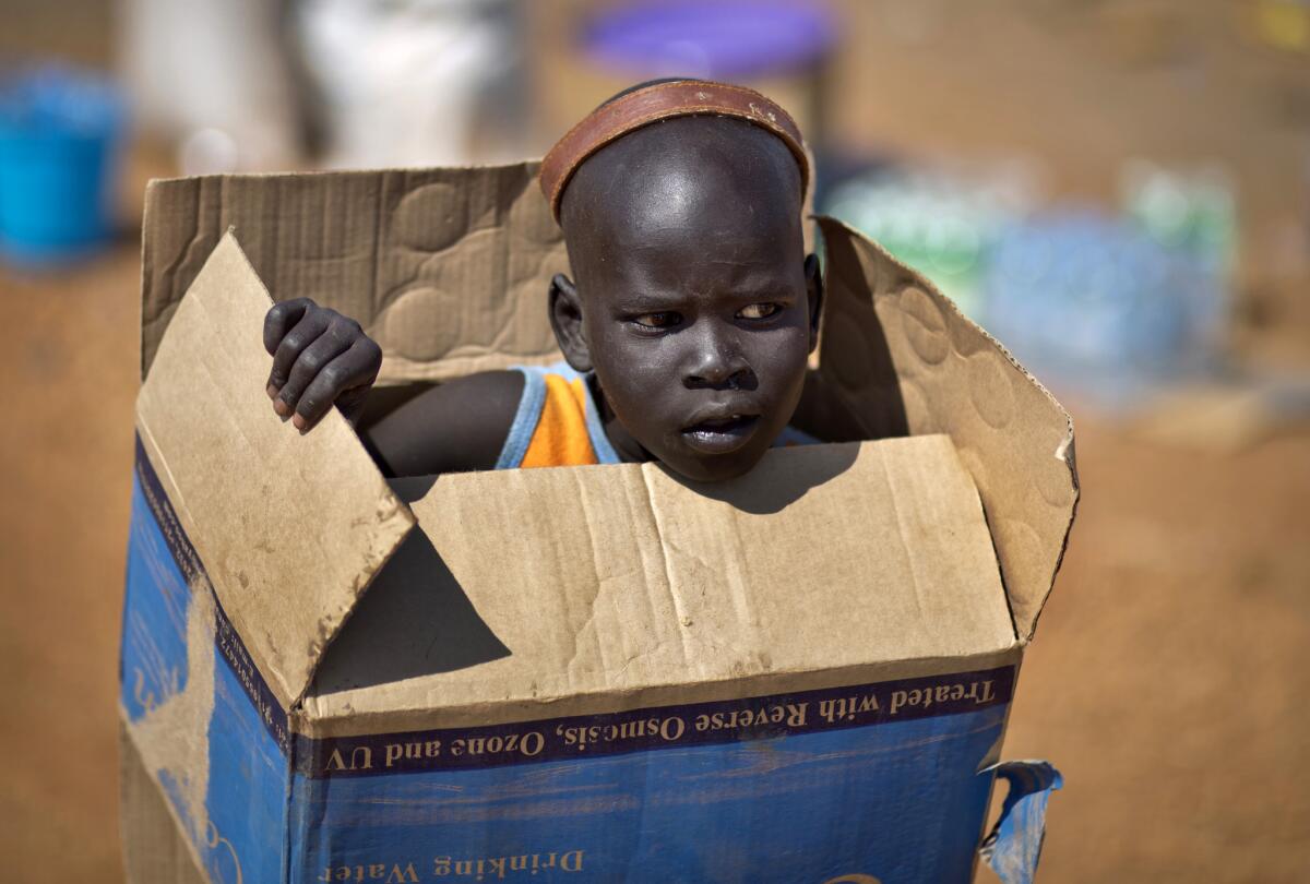 A displaced boy carries a cardboard box Friday at a United Nations compound in Juba, South Sudan, that has become home to thousands of people displaced by the recent fighting.