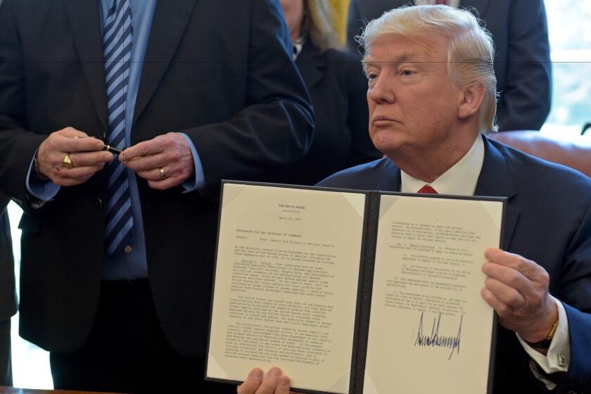 President Donald Trump show off the signed executive memorandum on investigation of steel imports, Thursday, April 20, 2017, in the Oval Office of the White House in Washington. United Steel Workers International President Leo W. Gerard, left, looks at the pen that was used to sign the document. (AP Photo/Susan Walsh)