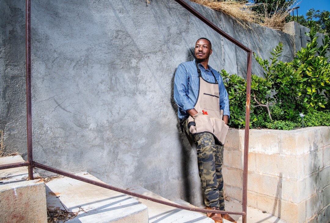 Ken Sparks leans against a concrete wall at his home garden in East Los Angeles.