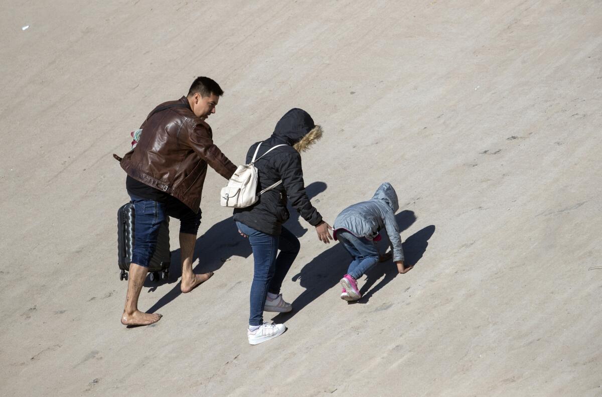 A family climbs a riverbank.