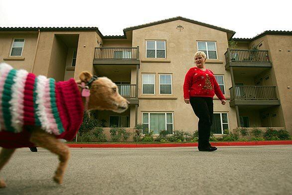 Jody Miller walks her dog outside the Stevenson Ranch apartment she and her husband rented after smoke from the Sayre fire severely damaged their Oakridge Park home. Her sister, who is living upstairs, lost everything. Only young children will get Christmas gifts as the families save to rebuild.