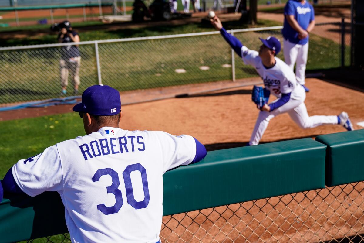 Dodgers manager Dave Roberts watches pitcher Walker Buehler during a spring training bullpen session at Camelback Ranch in Arizona on Feb. 20.
