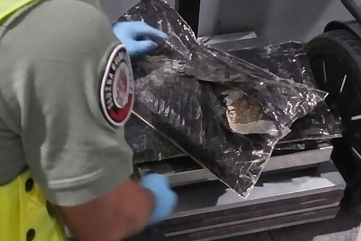 In this photo provided by the Polish National Fiscal Administration, a customs officer shows packages of heroin that were discovered in the luggage of a woman as she was transiting at Frederic Chopin airport in Warsaw, Poland, Sunday Aug. 14, 2022. A 81-year-old Danish woman traveling from Africa to Canada was arrested at Warsaw airport on suspicion of illegal possession of heroin worth over $515,000, officials in Poland said Friday. (Polish National Fiscal Administration via AP)