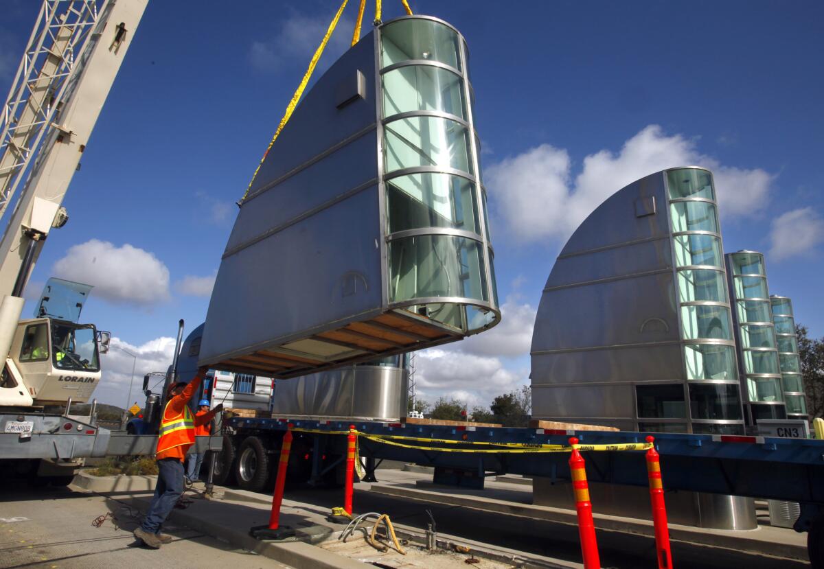 Crews remove a tollbooth from the toll plaza on the San Joaquin Hills toll road Thursday, a symbolic first step in the planned removal of all tollbooths in Orange County.