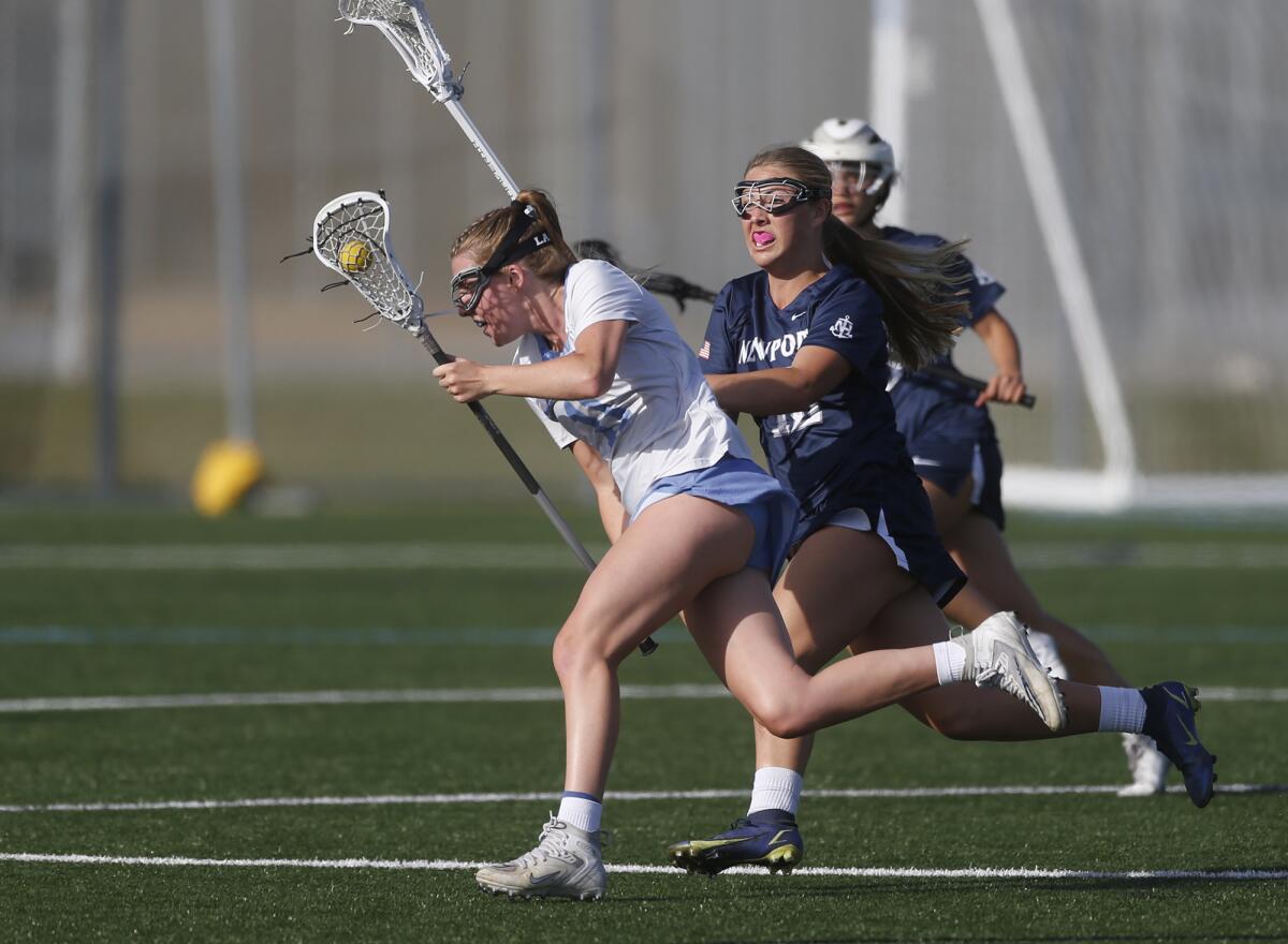 Corona del Mar's Abby Grace (11) wins the draw and runs the ball upfield during the Battle of the Bay girls' lacrosse match.