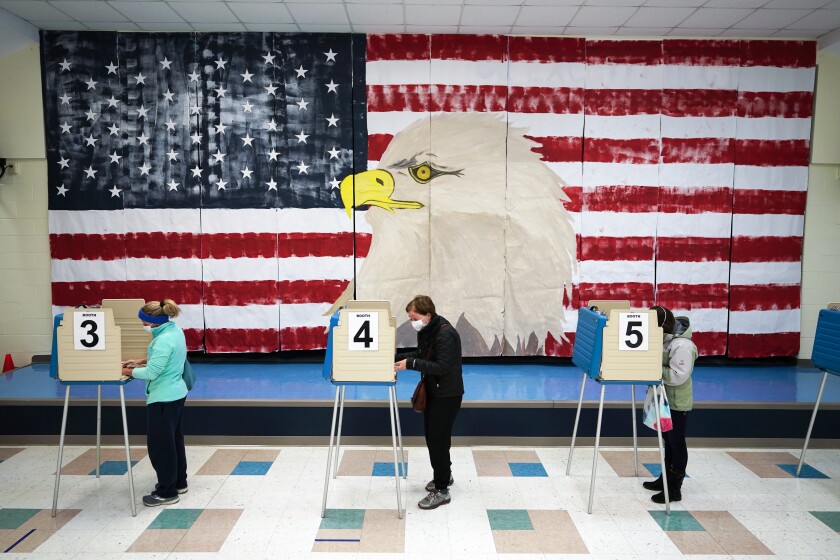 FILE - In this Nov. 3, 2020, file photo voters cast their ballots under a giant mural at Robious Elementary school on Election Day, in Midlothian, Va. Democrats are revising key sections of their sweeping legislation to overhaul U.S. elections, hoping to address the concerns raised by state and local election officials even as they face daunting odds of passing the bill through Congress. (AP Photo/Steve Helber, File)