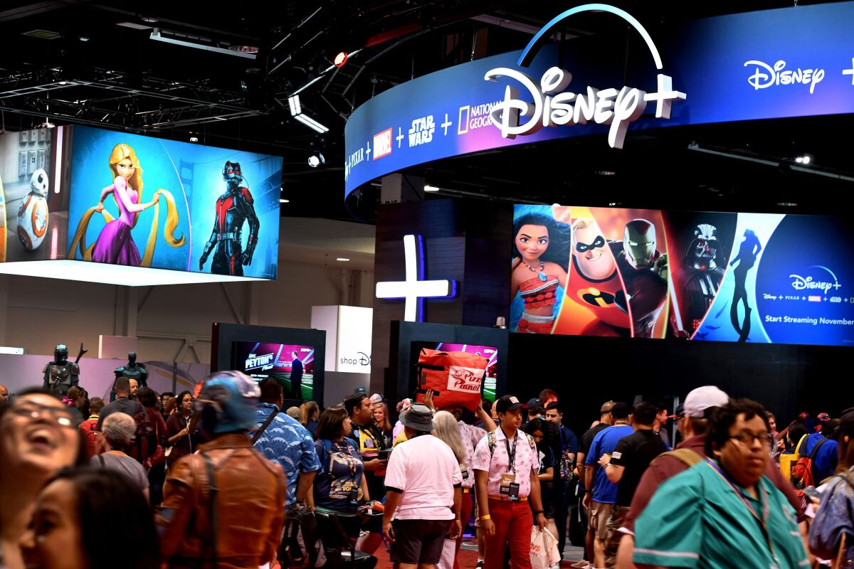 Attendees visit the Disney+ streaming service booth at D23 Expo 2019.