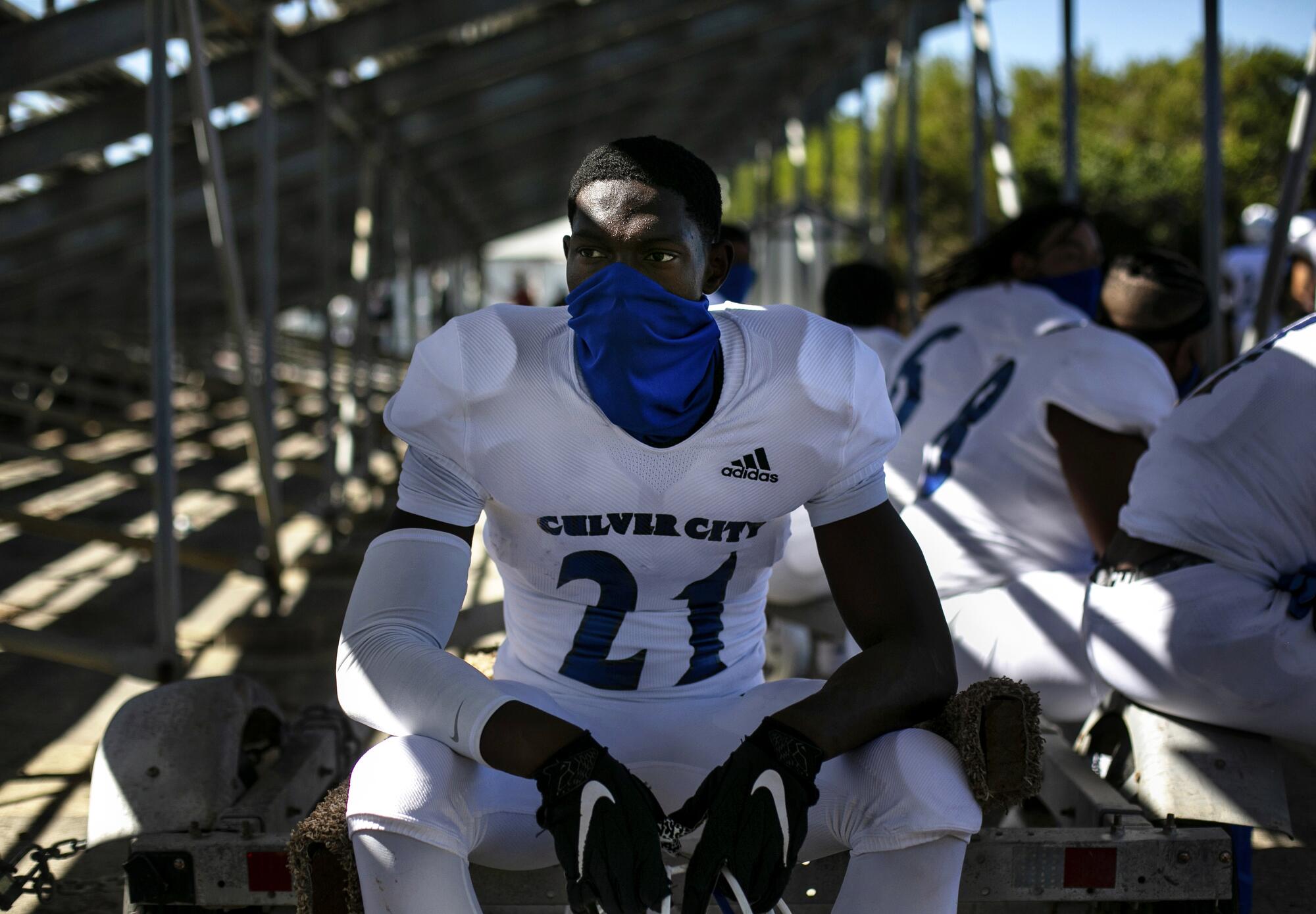 Prince Okorie (21) quietly sits under the bleachers with his team before taking the field.
