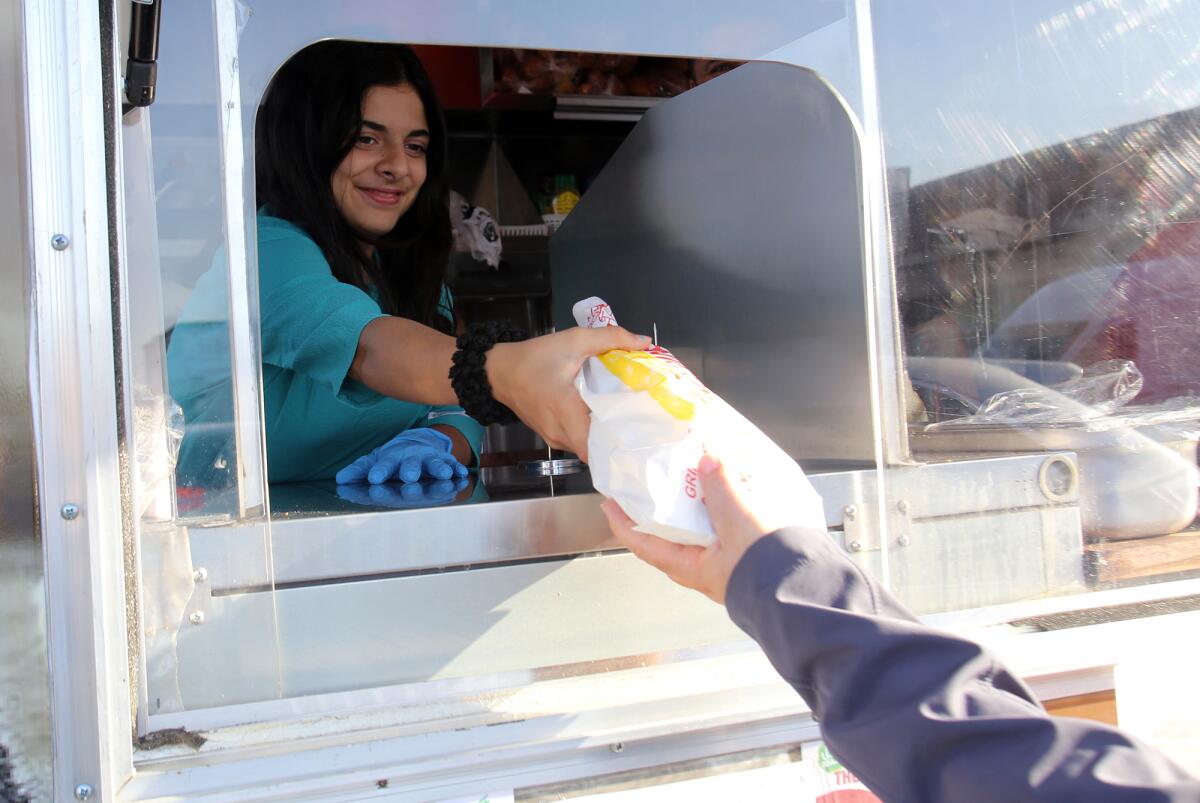 Zaina Morra, Sanad's daughter, hands out a sandwich to a customer.