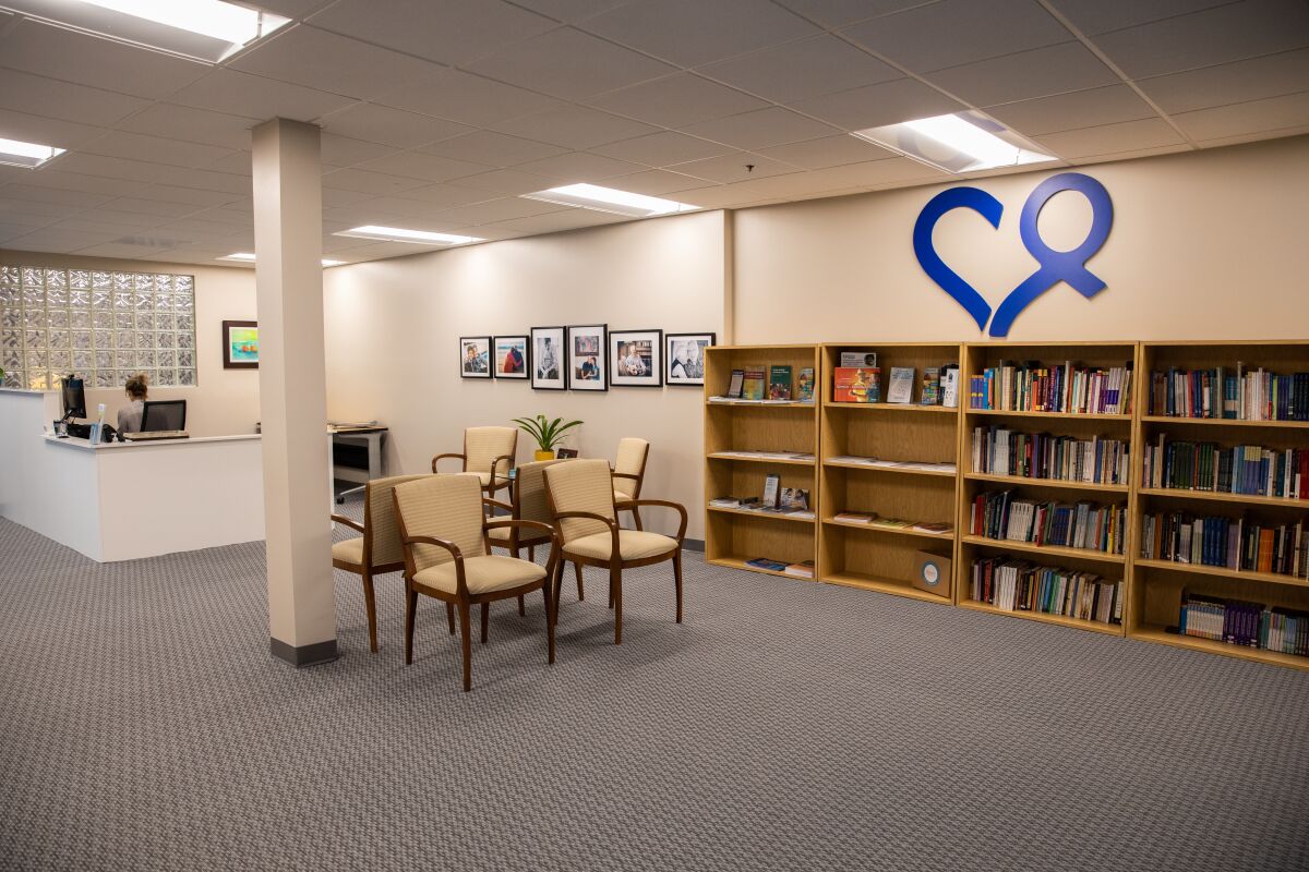 a waiting room in an office with four bookshelves on the back wall and a reception desk in the back left corner