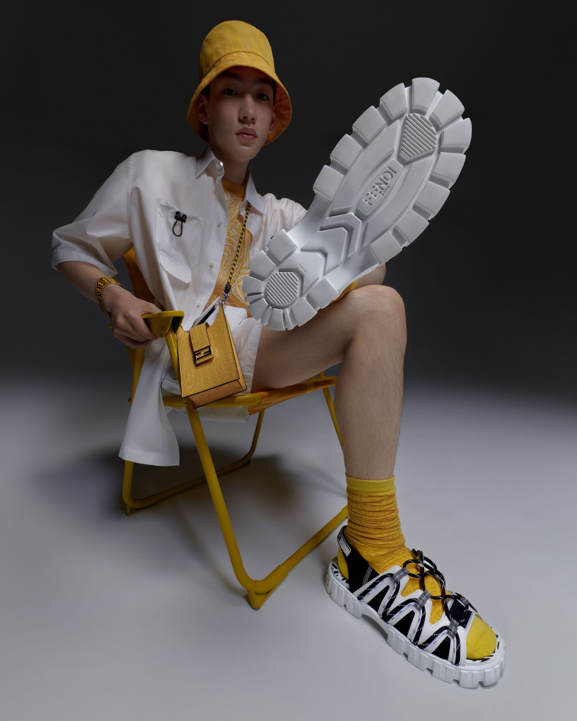 A man in a chair wearing items from the Fendi FF Vertigo summer capsule collection.