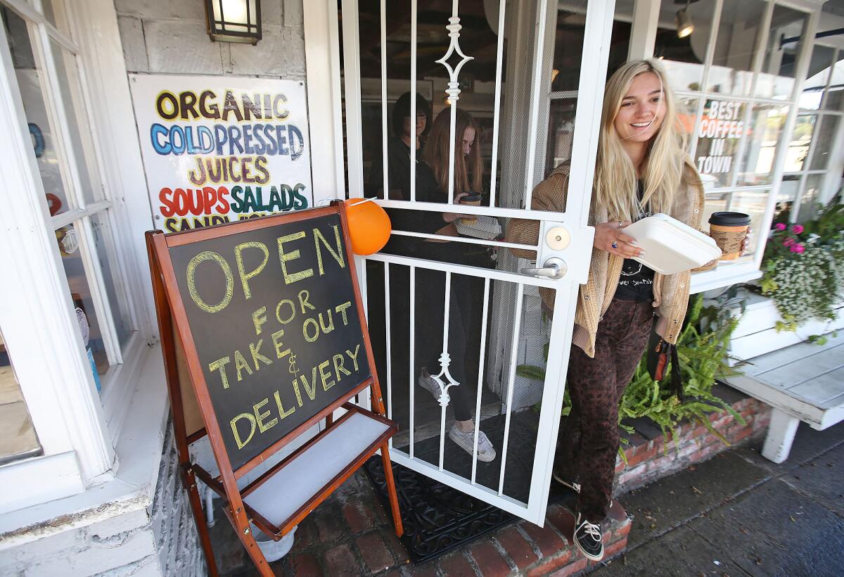 Rachel Miller, right, and sister Chloe get takeout sandwiches and coffee from Orange Inn in Laguna Beach.