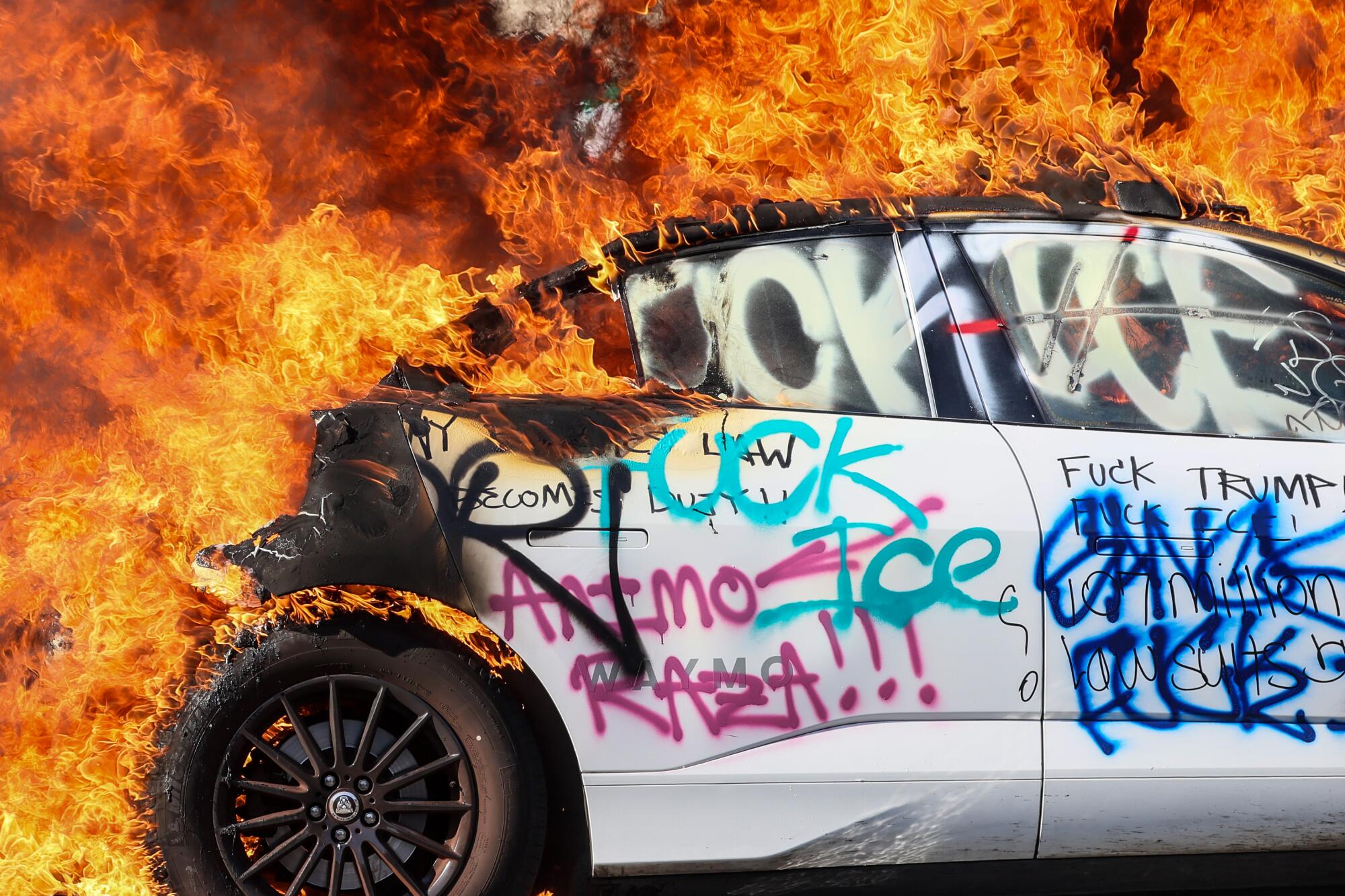 Flames erupt from a Waymo autonomous car covered with graffiti.