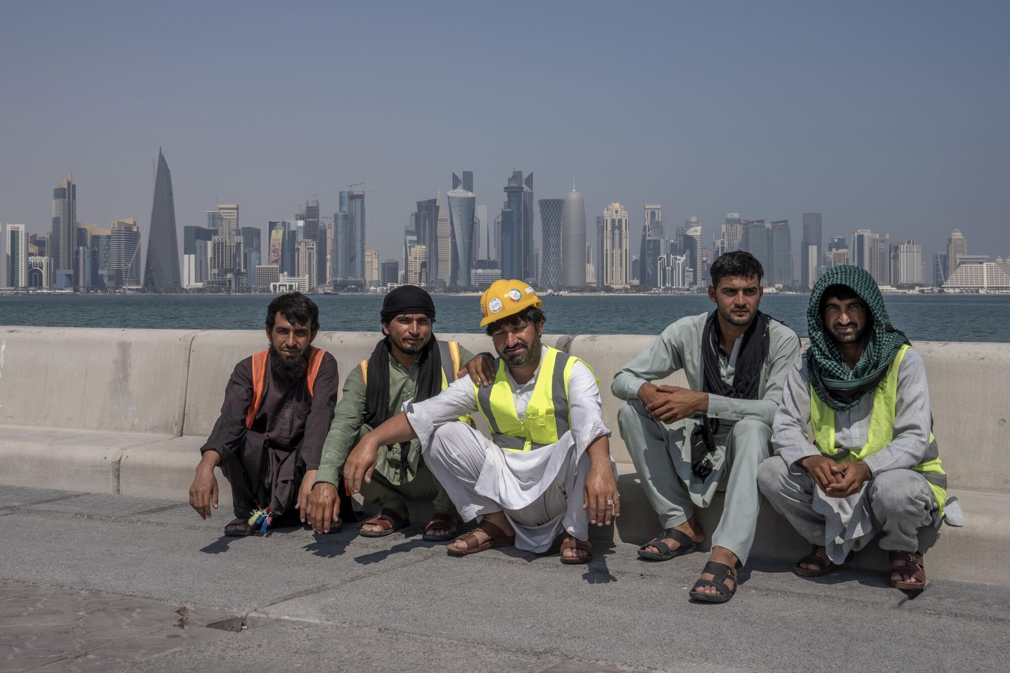 Pakistanlı göçmen işçiler Doha silüetinin önünde poz veriyor.