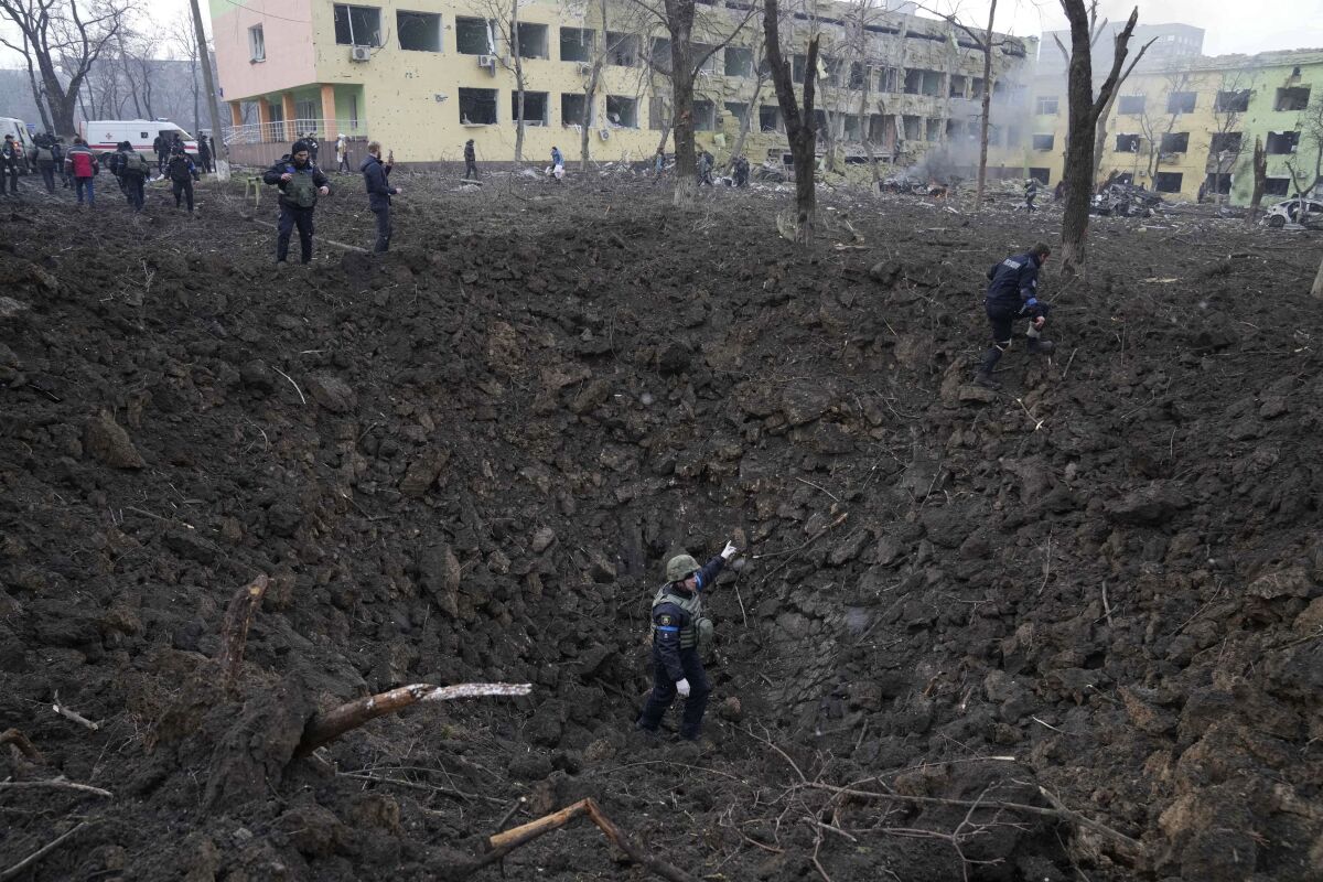 FILE - Ukrainian soldiers and emergency employees work outside a maternity hospital damaged by shelling in Mariupol, Ukraine, Wednesday, March 9, 2022. An Associated Press team of journalists was in Mariupol the day of the airstrike and raced to the scene. Their images prompted a massive Russian misinformation campaign that continues to this day. (AP Photo/Evgeniy Maloletka, File)