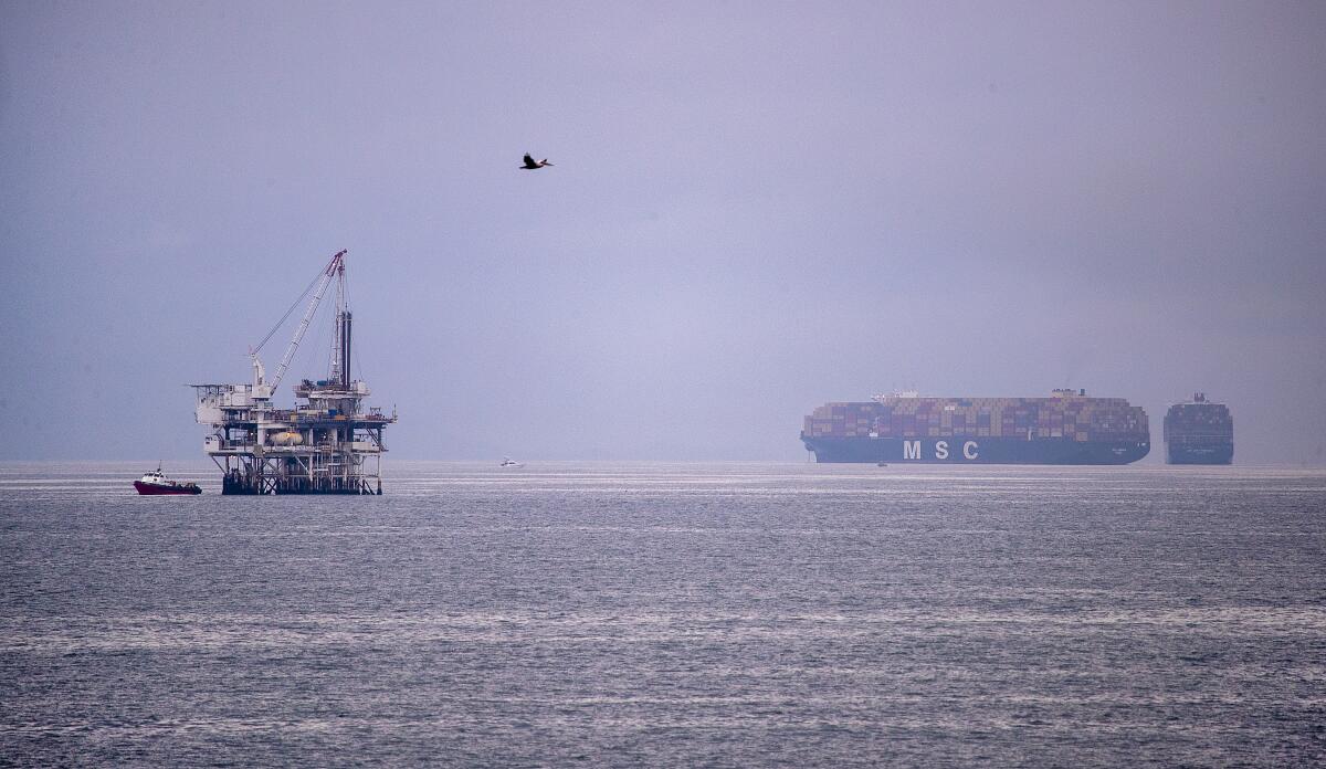 A pelican flies over an oil platform in the ocean