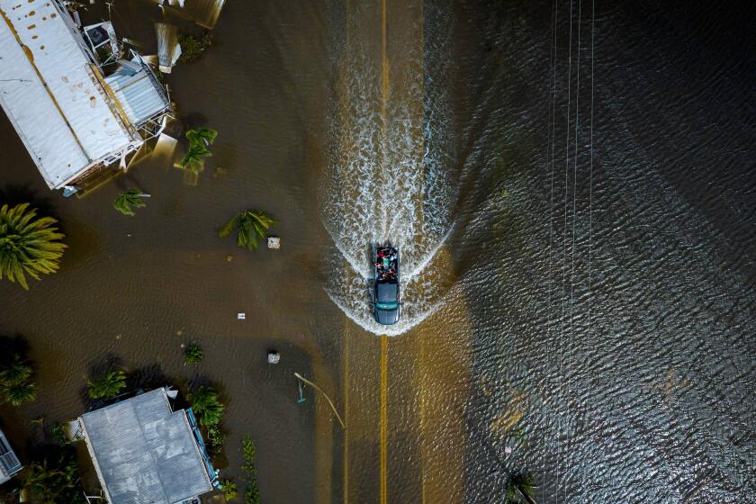 TOPSHOT - An aerial picture taken on September 29, 2022 shows a car driving through a flooded neighborhood in the aftermath of Hurricane Ian in Fort Myers, Florida. - Hurricane Ian left much of coastal southwest Florida in darkness early on Thursday, bringing "catastrophic" flooding that left officials readying a huge emergency response to a storm of rare intensity. The National Hurricane Center said the eye of the "extremely dangerous" hurricane made landfall just after 3:00 pm (1900 GMT) on the barrier island of Cayo Costa, west of the city of Fort Myers. (Photo by Ricardo ARDUENGO / AFP) (Photo by RICARDO ARDUENGO/AFP via Getty Images)
