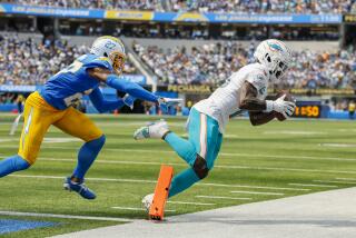 Dolphins receiver Tyreek Hill catches a pass near the goal line as Chargers cornerback J.C. Jackson pursues.