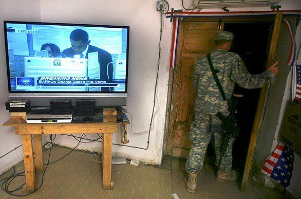 A U.S. soldier leaves the dining facility at his base in Kunar province in eastern Afghanistan as a live television feed shows Democratic presidential candidate Barack Obama voting in Chicago. Members of the U.S. military overseas were able to vote by absentee ballot.