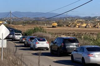Traffic backs up Thursday afternoon on North River Road, as earth-moving equipment crosses the road.