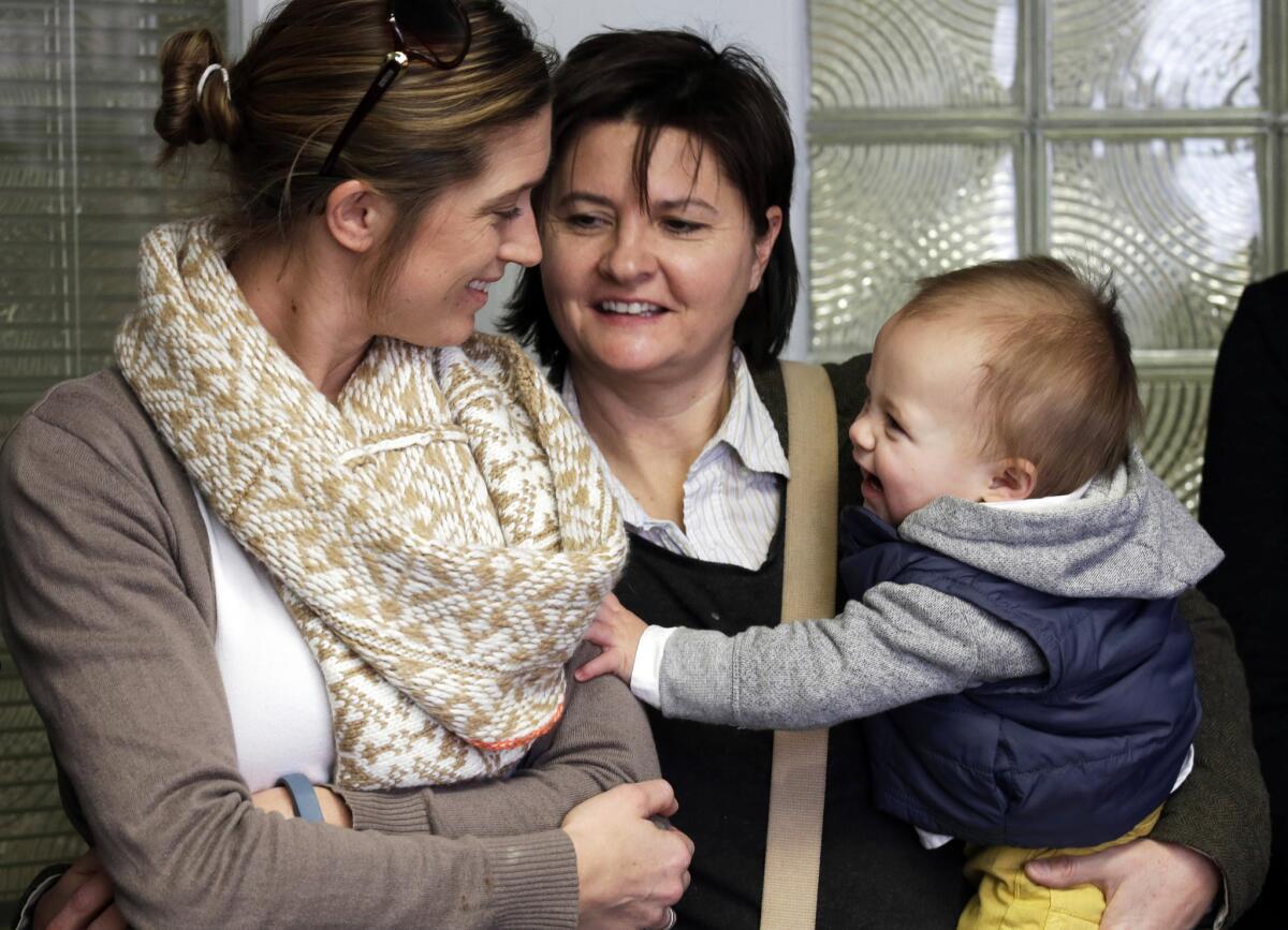 Amanda Broughton, left, looks at one of her twin sons, held by her partner, Michele Hobbs, during a news conference in Cincinnati. Four legally married gay couples sought a court order to force Ohio to recognize same-sex marriages on birth certificates despite a statewide ban.