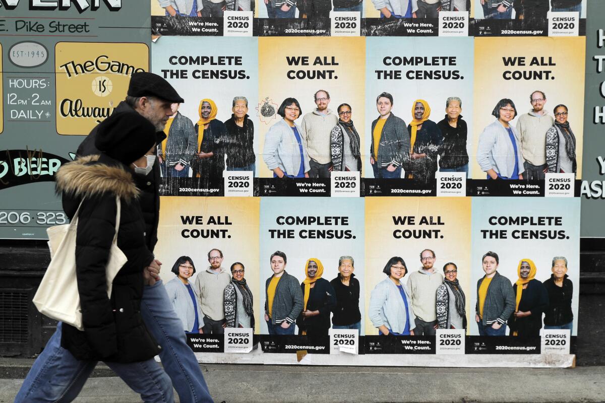People walk past posters encouraging participation in the 2020 census