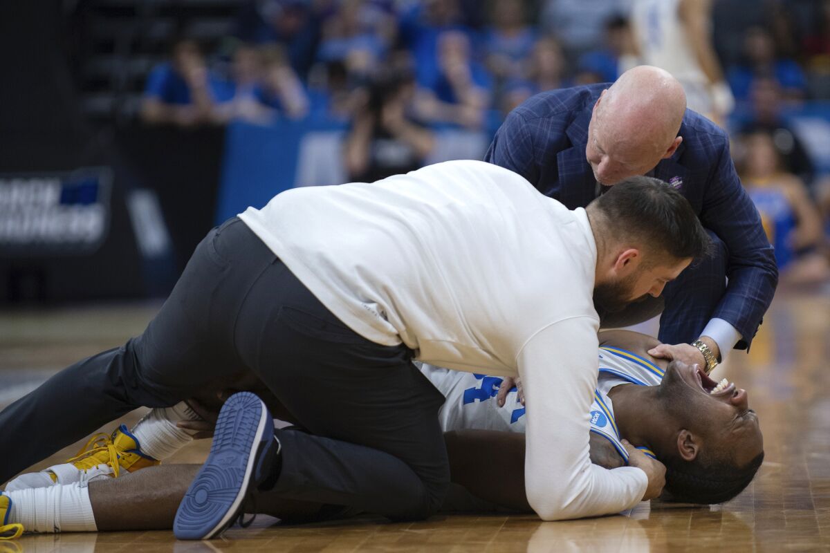 UCLA guard David Singleton yells while being treated by the team trainer, as coach Mick Cronin joins them, during the second half of the team's second-round college basketball game against Northwestern in the men's NCAA Tournament, Saturday, March 18, 2023, in Sacramento, Calif. UCLA won 68-63. (AP Photo/José Luis Villegas)