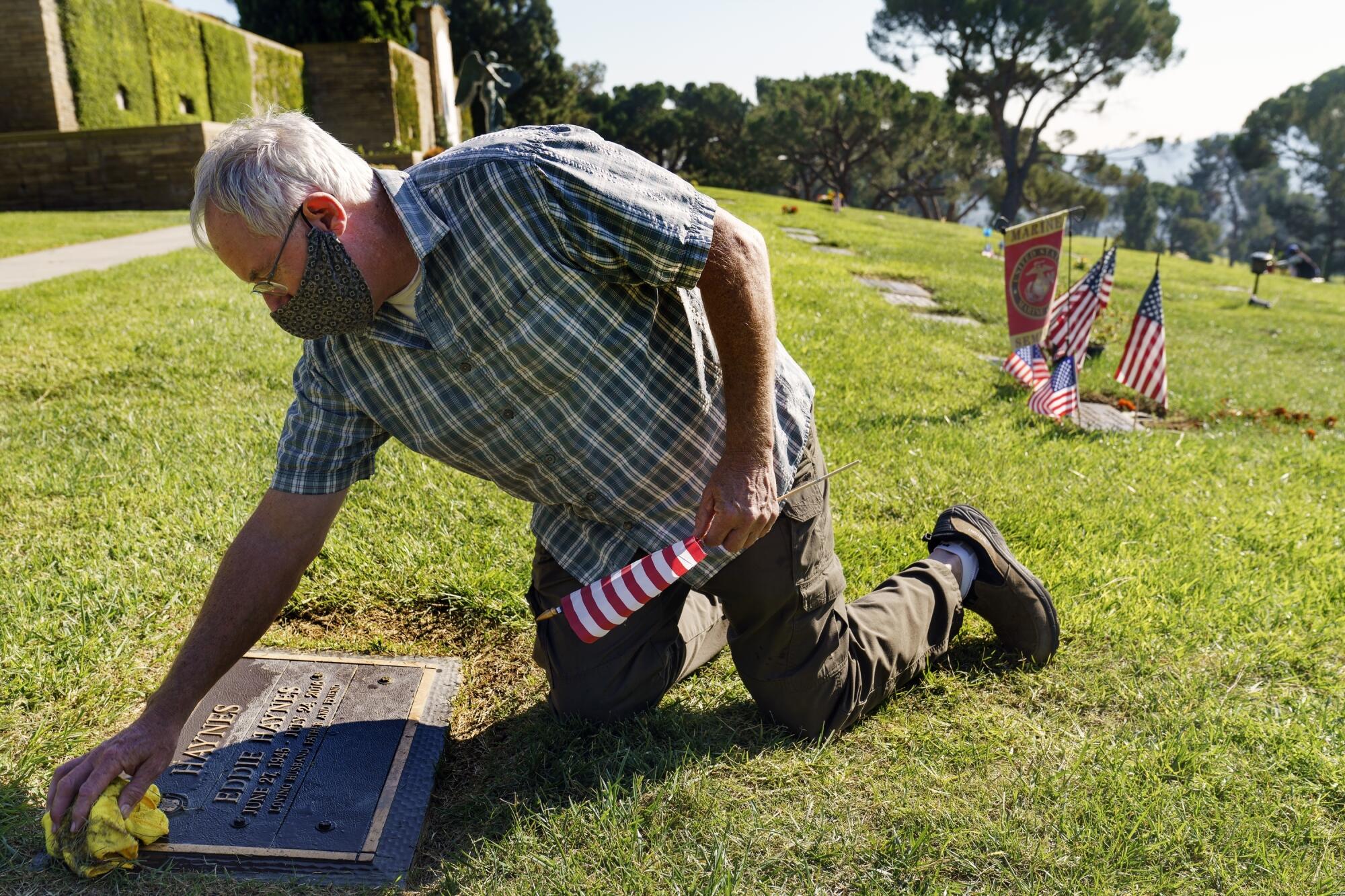 A man wipes down a headstone in the grass