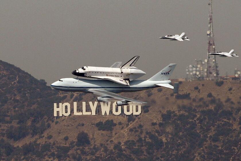 The space shuttle Endeavour passes the Hollywood sign.