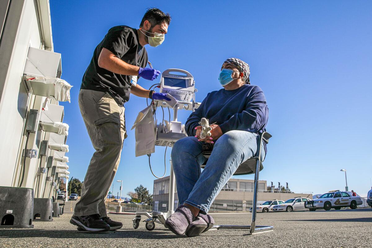 Registered nurse Rafael Sanchez, left, evaluates COVID-19 patient.