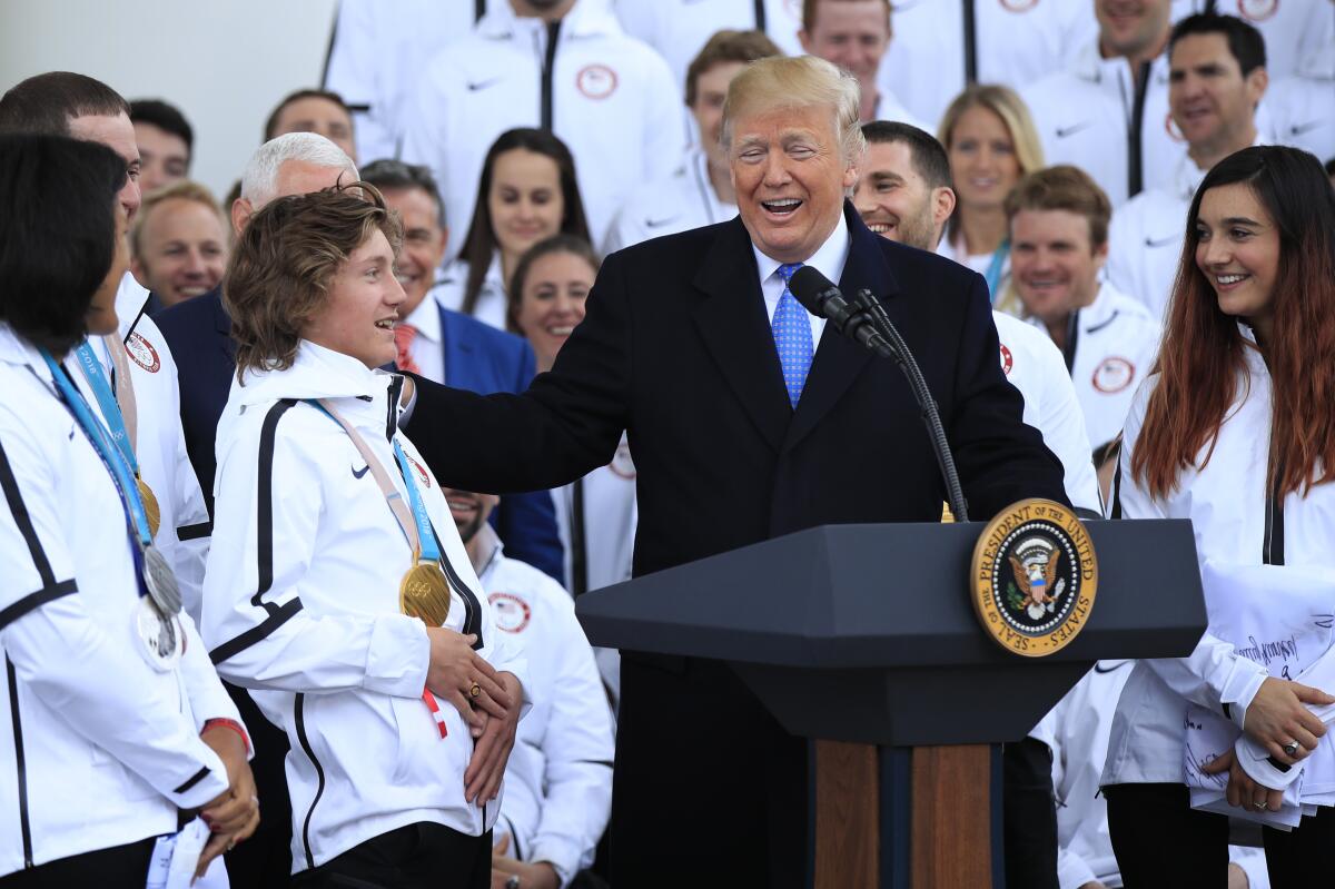 Donald Trump surrounded by Olympic athletes wearing matching white jackets